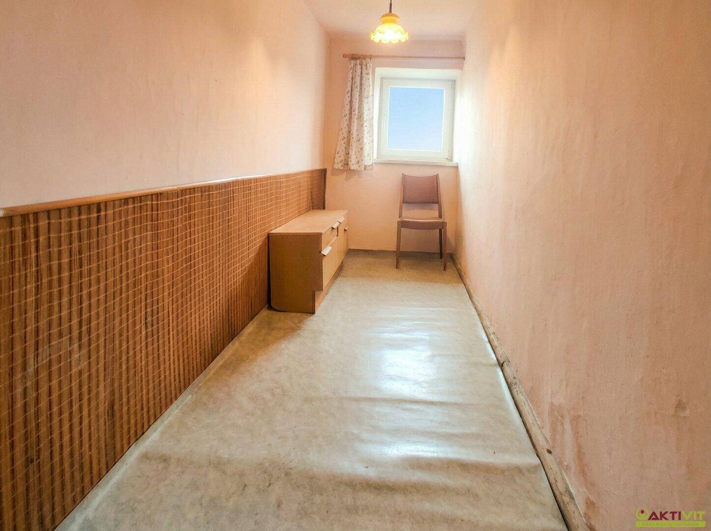 Schmaler Raum mit rosa Wänden, Holzverkleidung und Fenster.