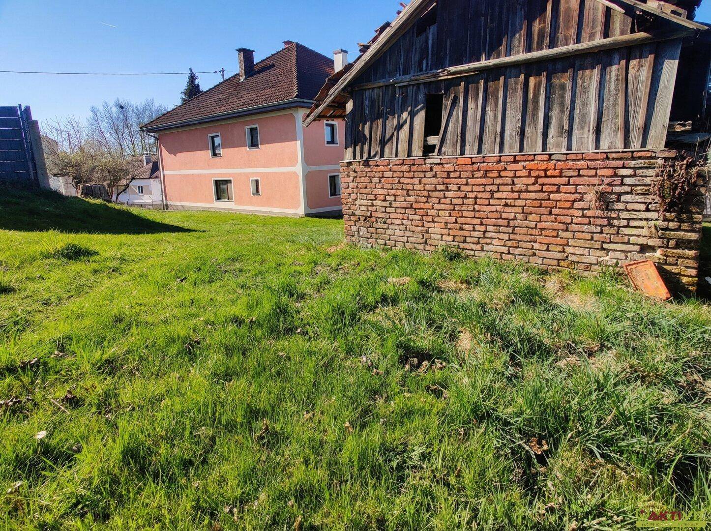 Ansicht des Wohnhauses und der Scheune mit üppigem Grün im Vordergrund.