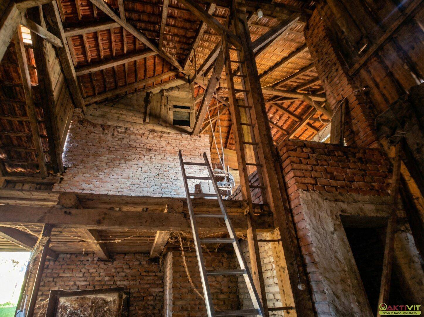 Hoher Dachboden mit sichtbarer Holzkonstruktion und Ziegelwänden.