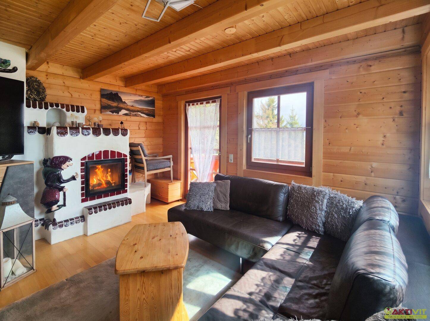 Wohnzimmer mit traditionellem Kaminofen, Holzwänden und bequemer Ledercouch.