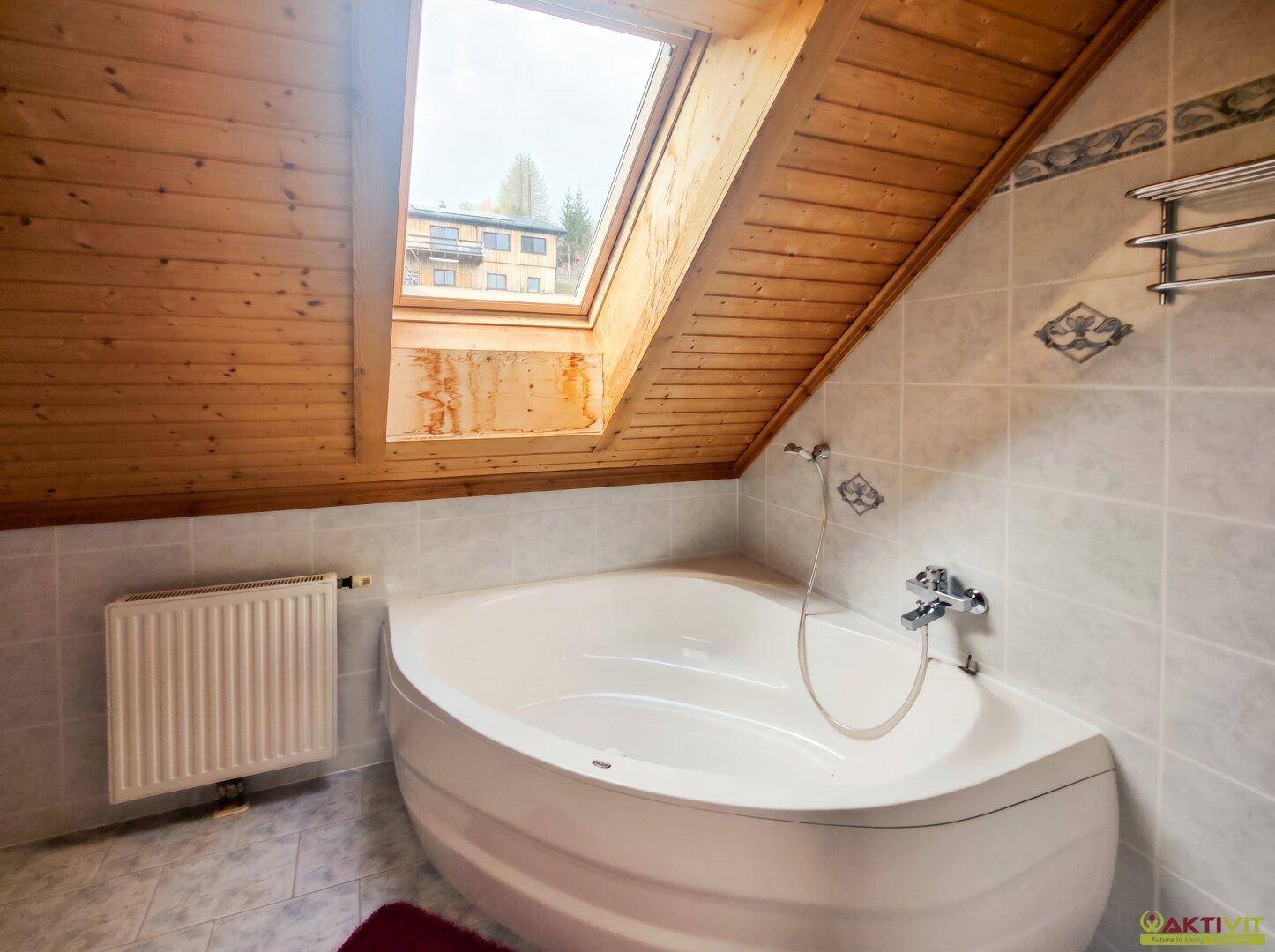 Badezimmer im Dachgeschoss mit Eckbadewanne, Fliesen und Dachschräge.