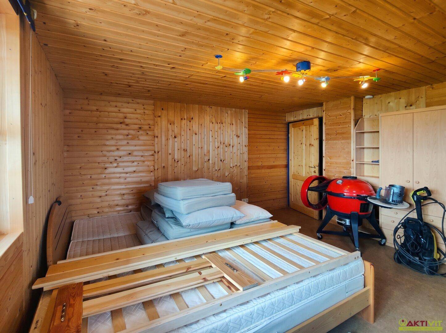 Geräumiger Raum mit Holzwänden, Bett und Stauraum, vielseitig nutzbar.