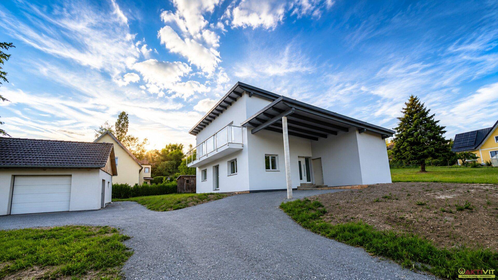 Freistehendes Einfamilienhaus mit Carport, Balkon und großem Grundstück unter sonnigem Himmel.