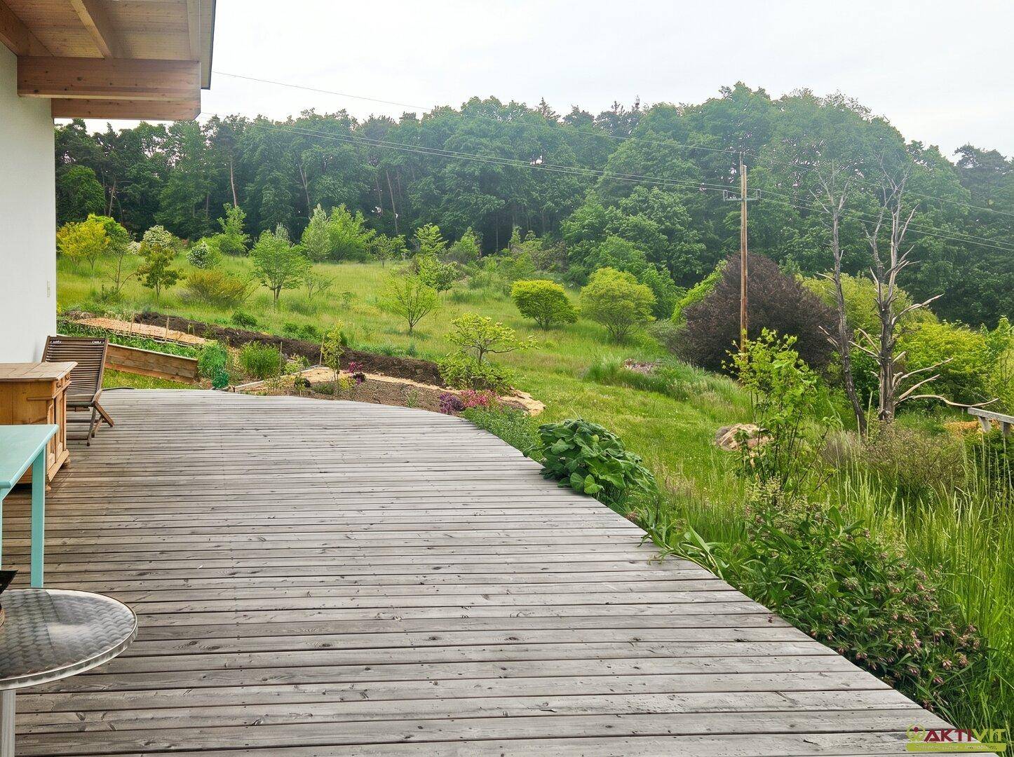 Große Holzterrasse mit weitem Blick über die grüne Hügellandschaft und Bäume.