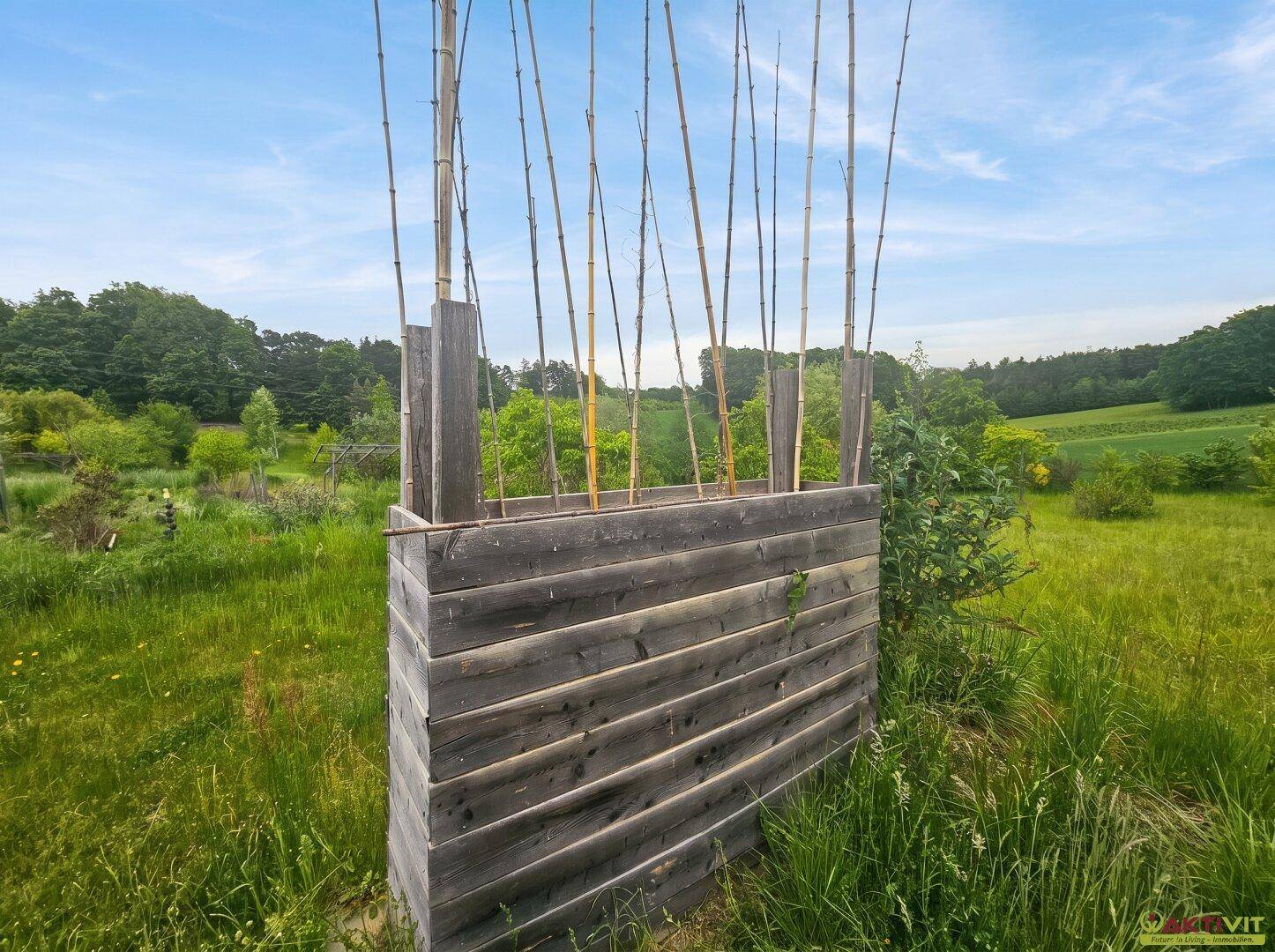 Holzkonstruktion in der Wiese, möglicherweise als Rankhilfe oder Sichtschutz.