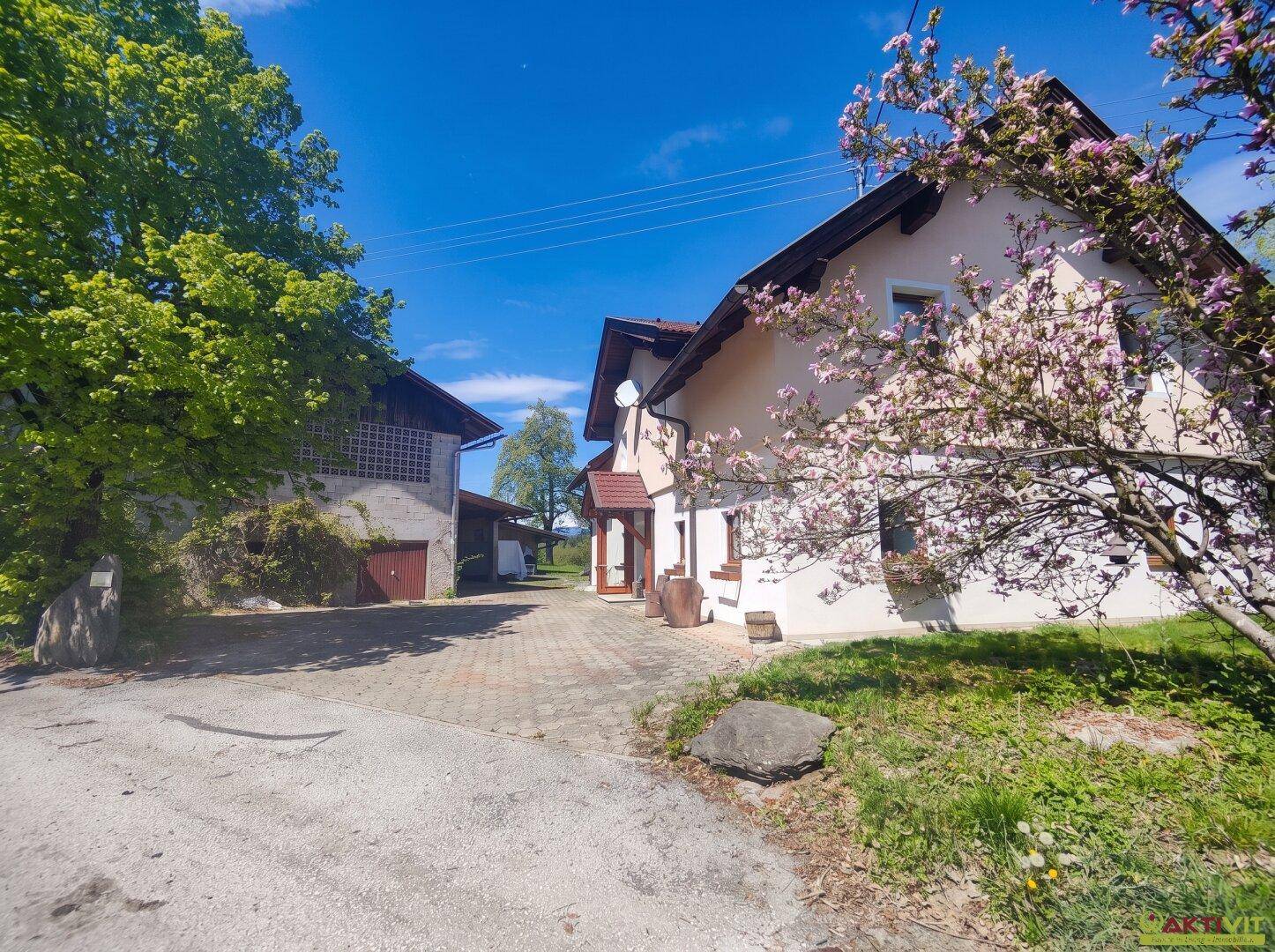 Ländliches Anwesen mit Haupthaus und Nebengebäude, umgeben von blühenden Bäumen und Natur.