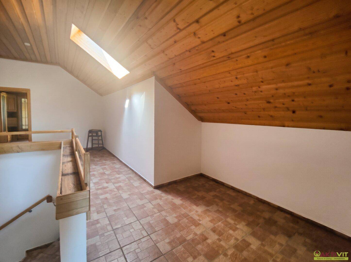Heller Dachgeschossflur mit Holzdecke, Fliesenboden und einem Oberlicht, das viel Licht spendet.