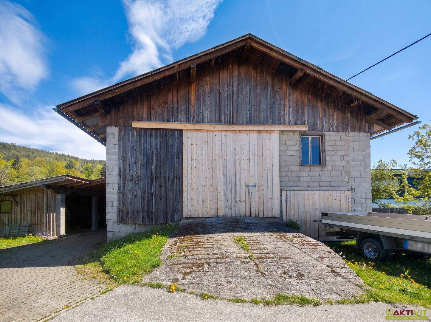 Große Scheune mit Holztoren und Betonsteinwänden, Teil eines ländlichen Anwesens.