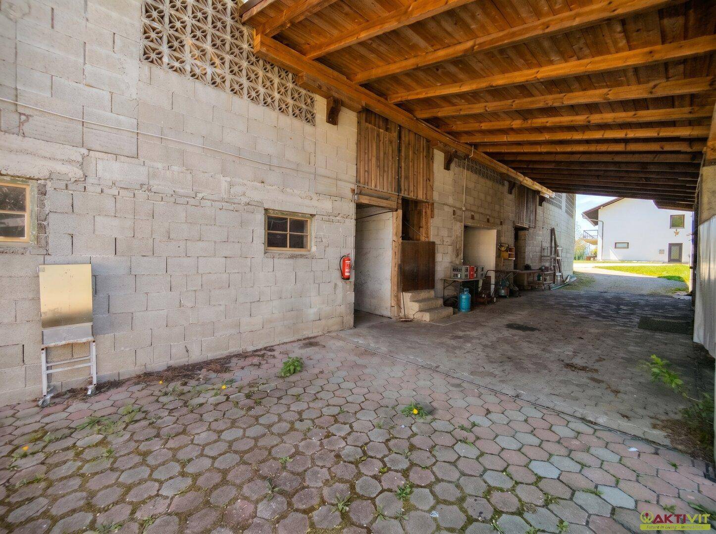 Überdachter Bereich mit Betonsteinwänden und Holzdecke, ideal als Carport oder Lagerfläche.