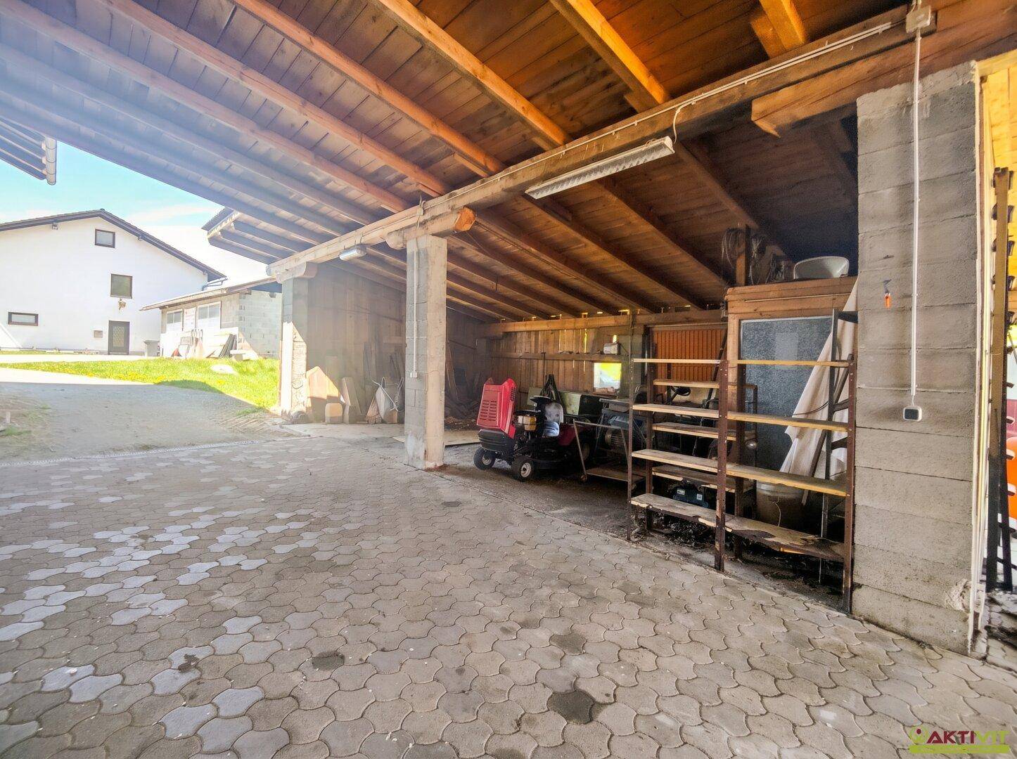 Geräumiger überdachter Bereich mit Holzdecke und Lagerregalen, vielseitig nutzbar.