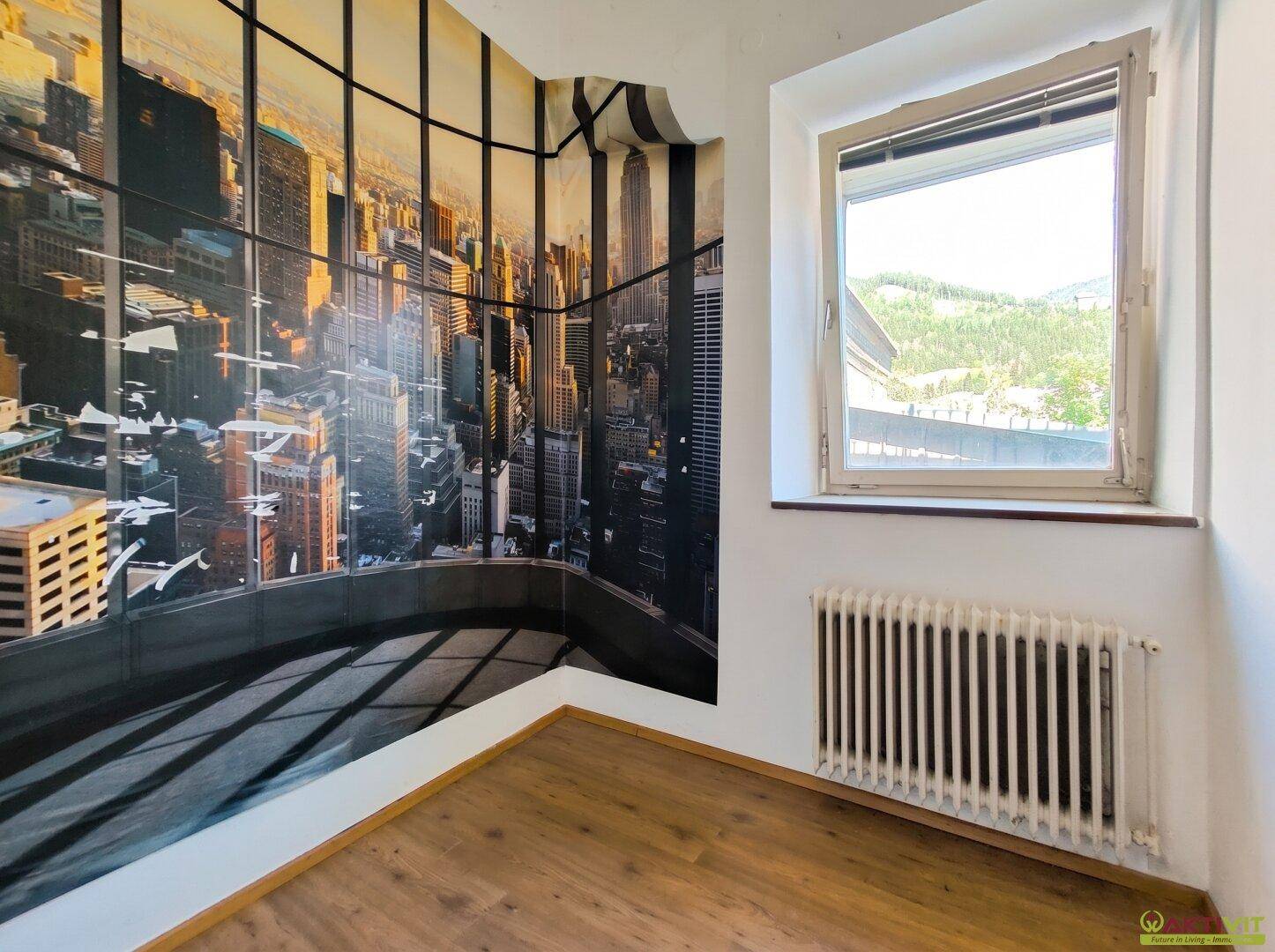 Schlafzimmer mit großer Stadtsilhouetten-Tapete und Fenster mit Blick ins Grüne.