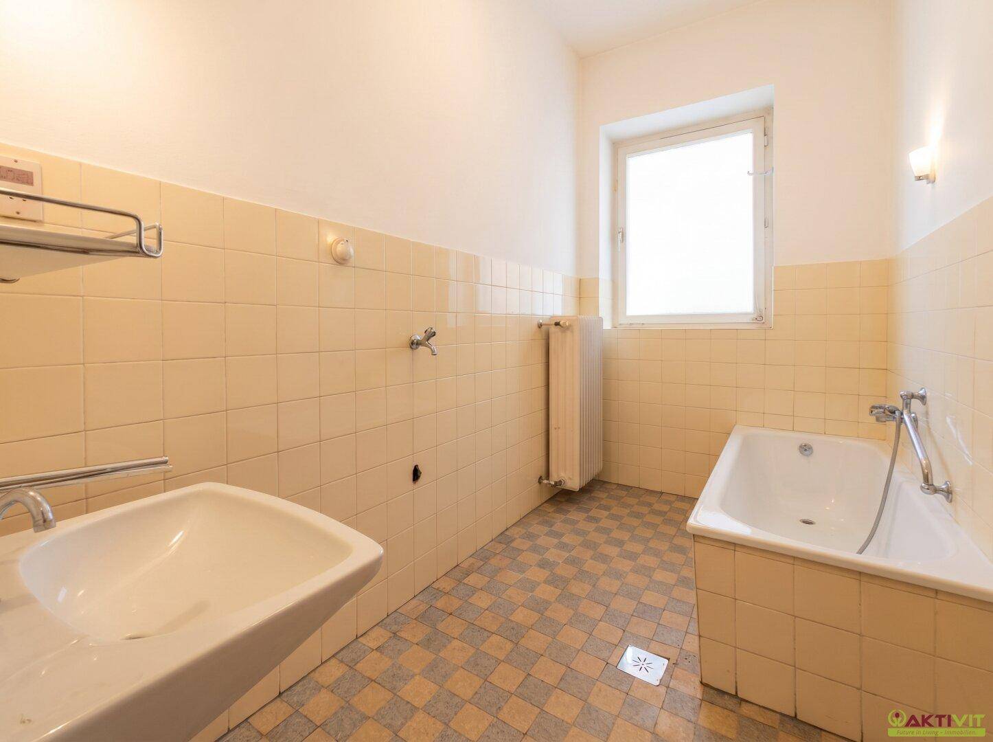 Badezimmer mit gelben Fliesen, Waschbecken, Badewanne und einem Fenster.