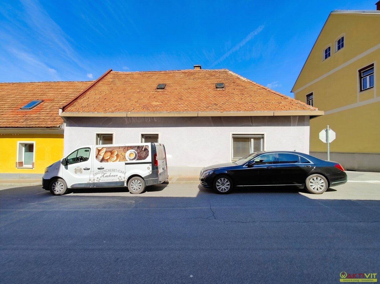 Fassadenansicht des Hauses von der Straße aus mit geparkten Autos davor.