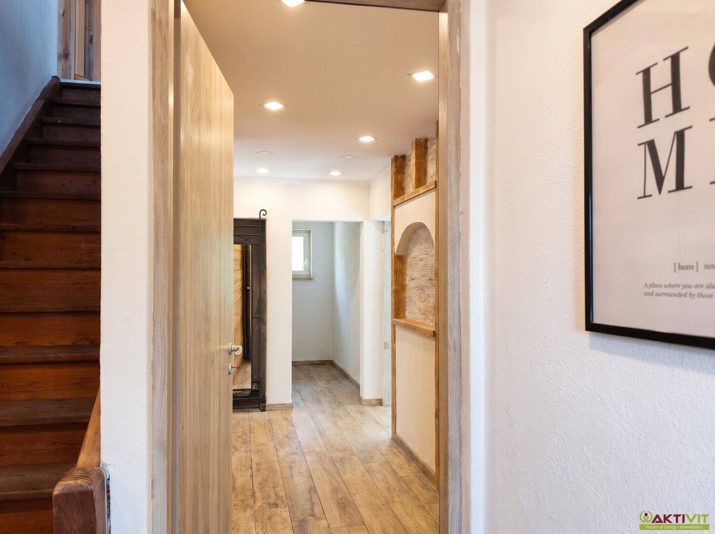 Heller Flur mit Holztreppe und Holzboden, der zu weiteren Räumen führt.