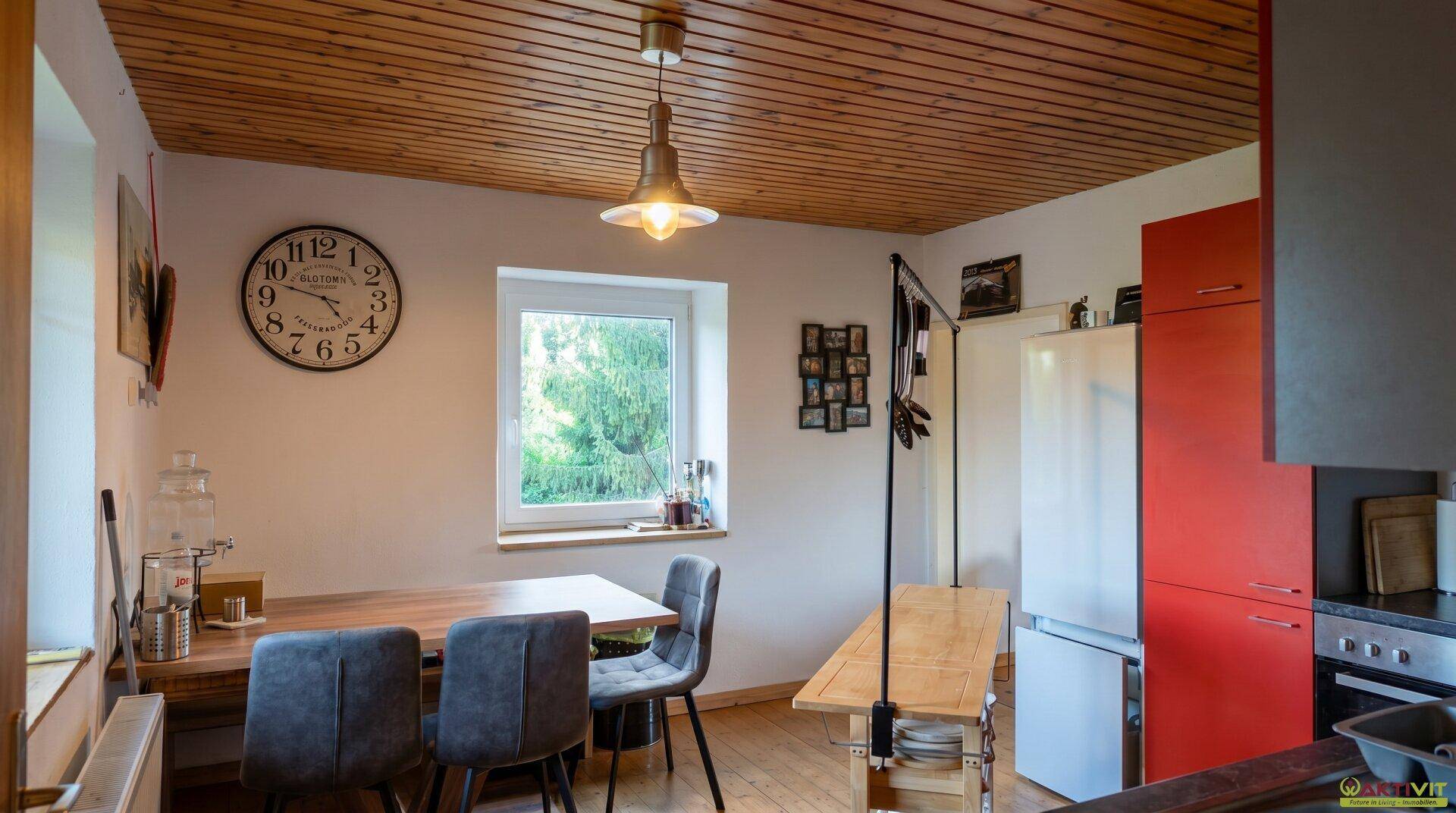 Essbereich in der Küche mit Holztisch, Stühlen und Holzdecke.