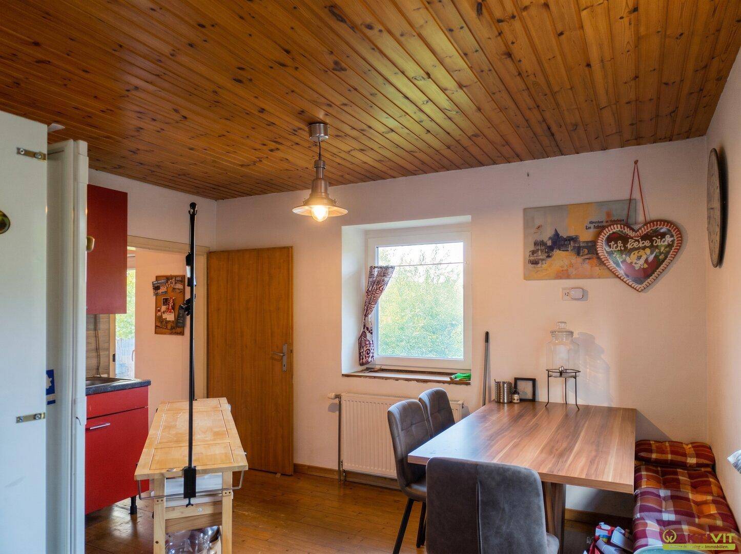 Essbereich in der Küche mit Holztisch, Stühlen und Blick aus dem Fenster.