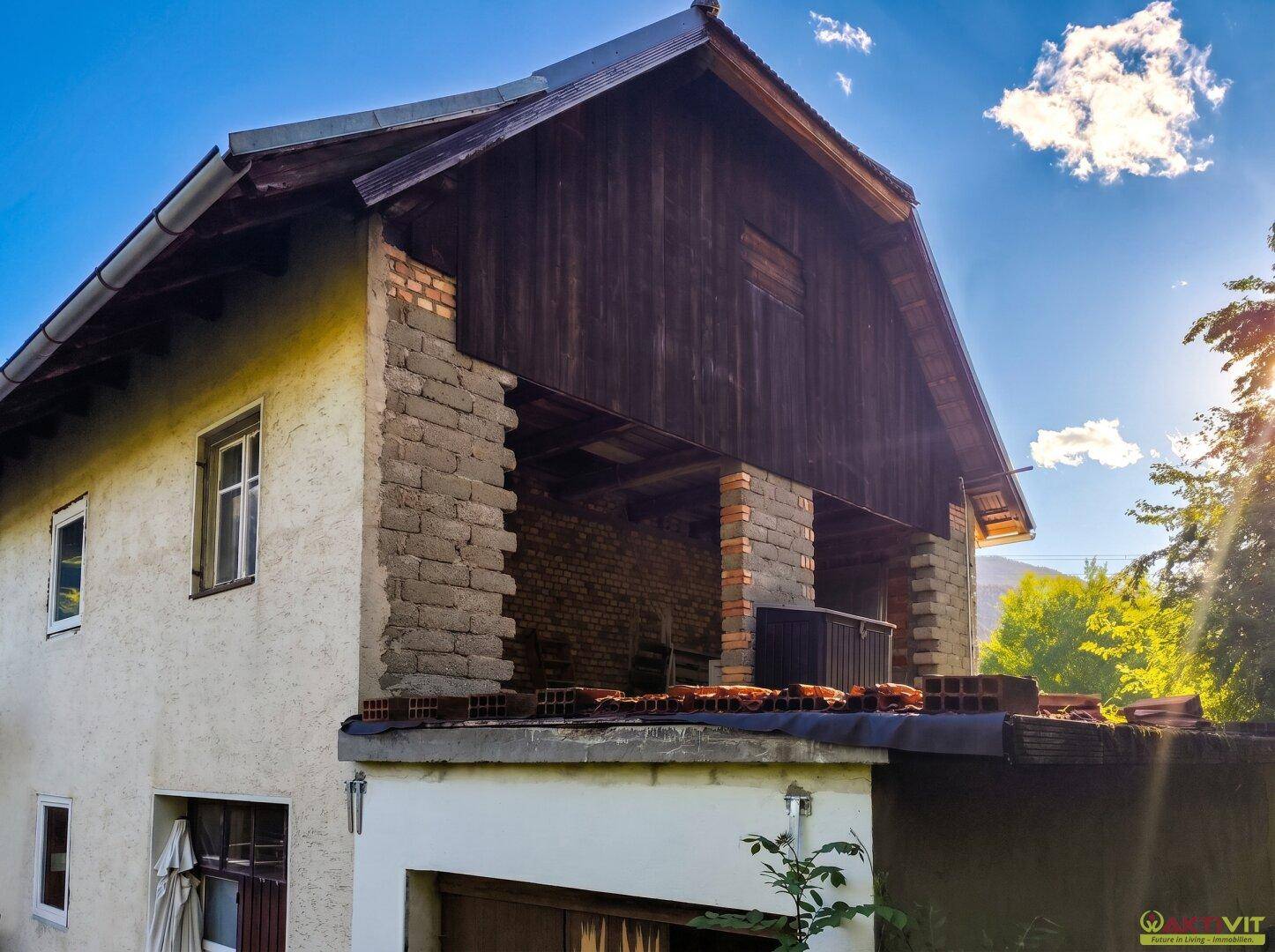 Seitenansicht des Hauses im Umbau mit sichtbaren Ziegeln und Holzelementen.
