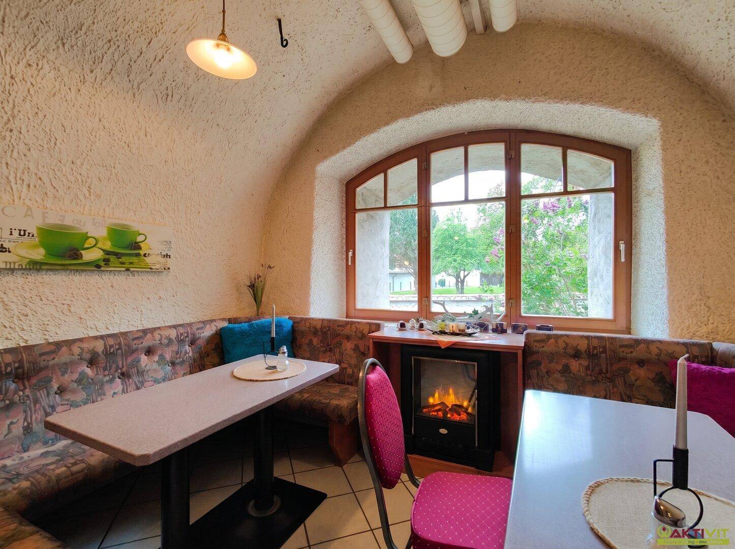 Gemütliche Sitzecke mit gewölbter Decke, großem Fenster und dekorativem Kamin.