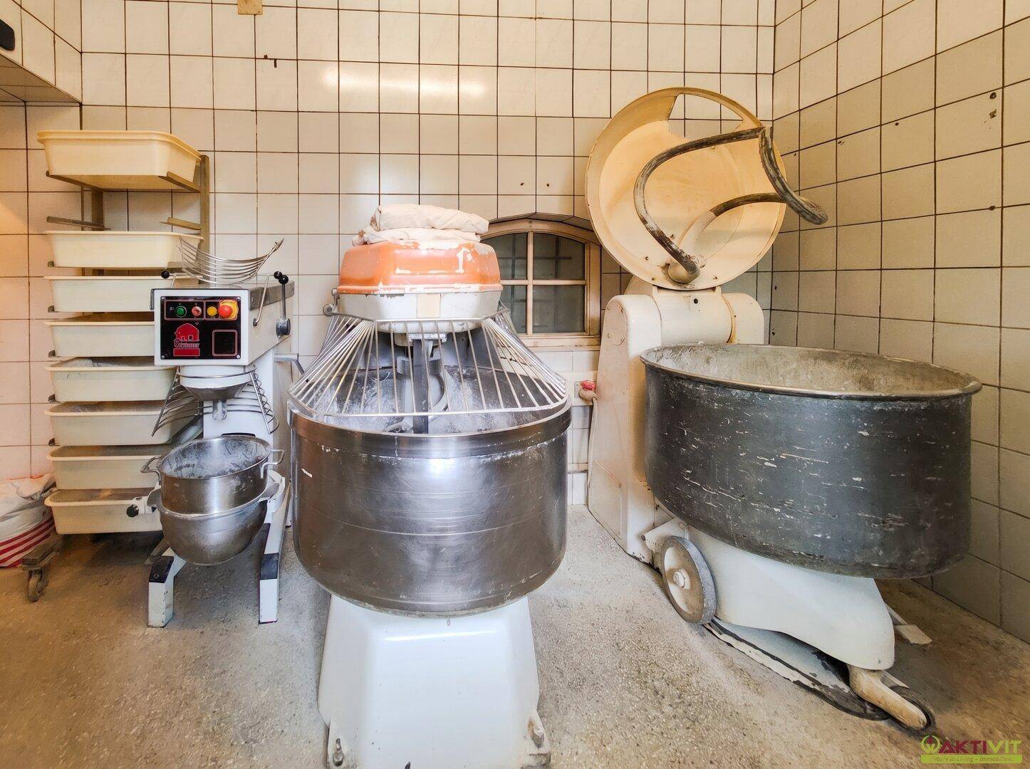 Produktionsbereich einer Bäckerei mit großen Teigknetmaschinen und gefliesten Wänden.
