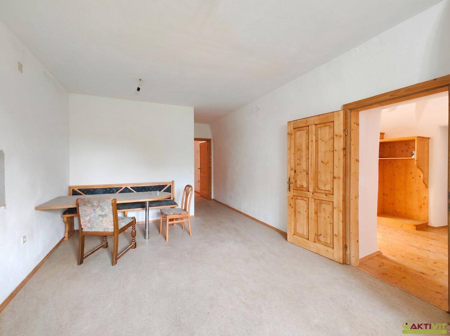Heller Raum mit Teppichboden, einer eingebauten Holzbank und einer Holztür.