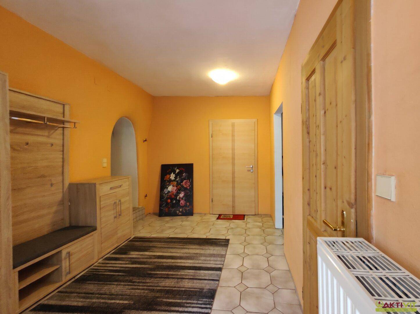 Flur mit orangefarbenen Wänden, Fliesenboden und eingebauter Holzgarderobe.