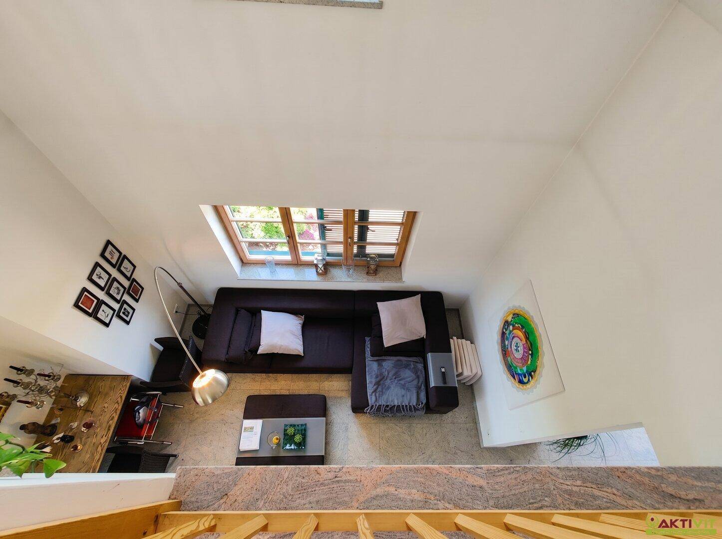 Blick von oben auf den gemütlichen Wohnbereich mit Sofa und Dachfenster.