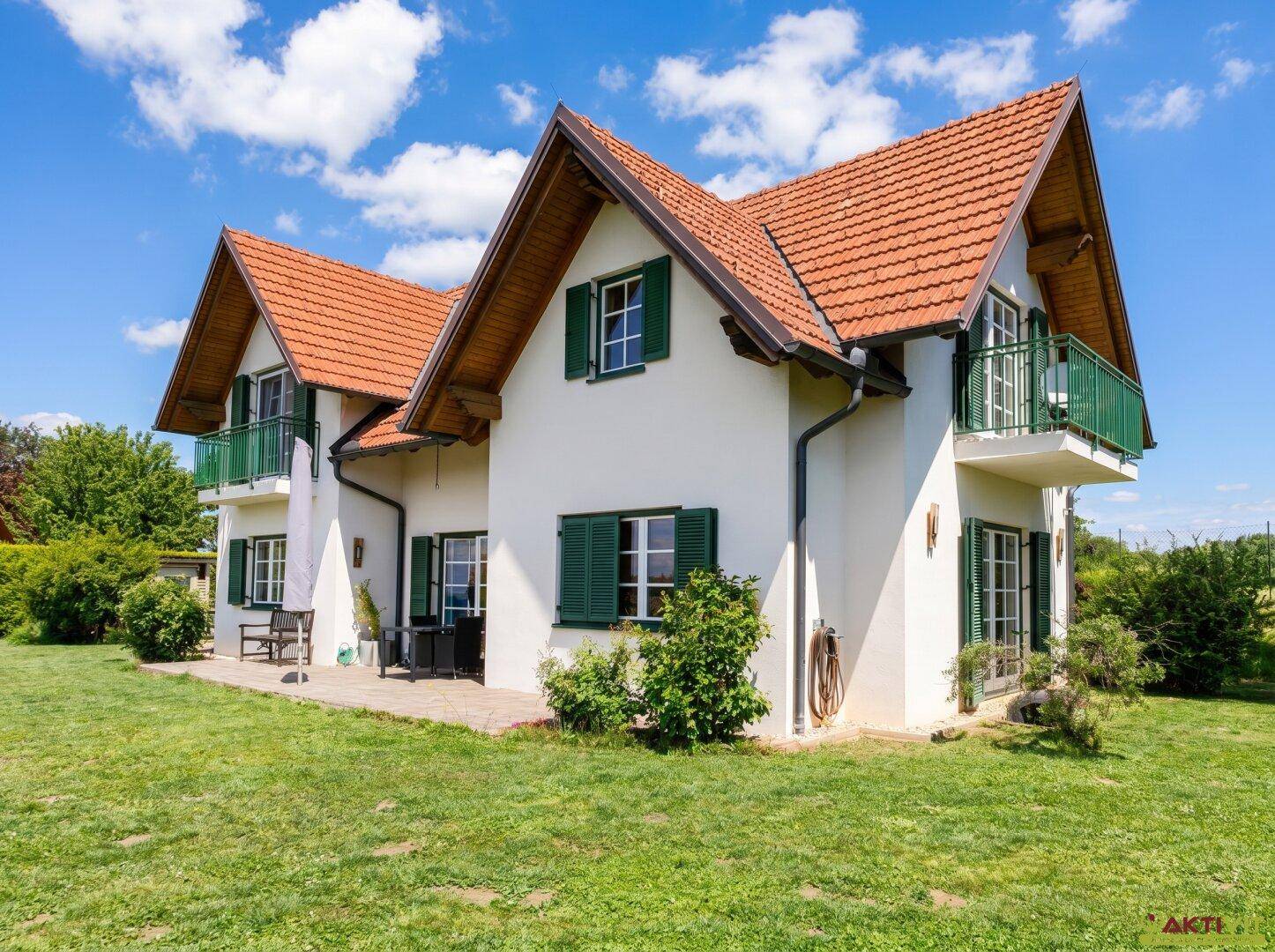 Seitlicher Gartenbereich mit Rasen, kleiner Terrasse und Zugang zum Haus.