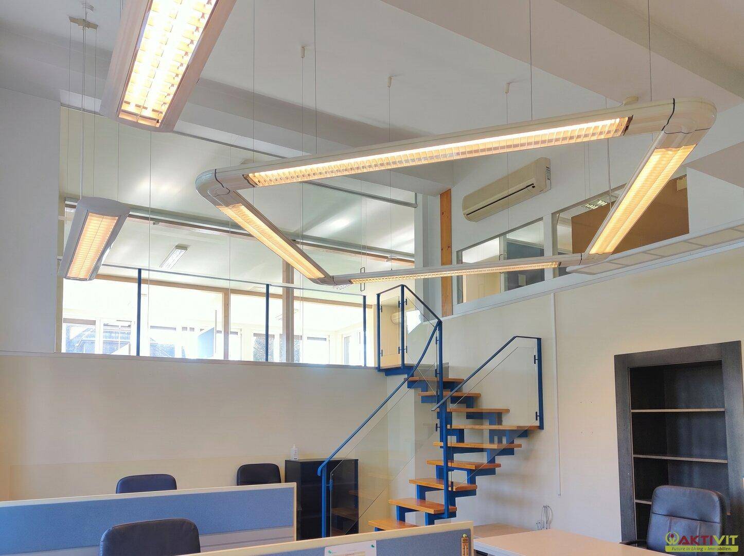 Bürofläche mit offener Treppe, Glasgeländer und Blick auf weitere Arbeitsbereiche.