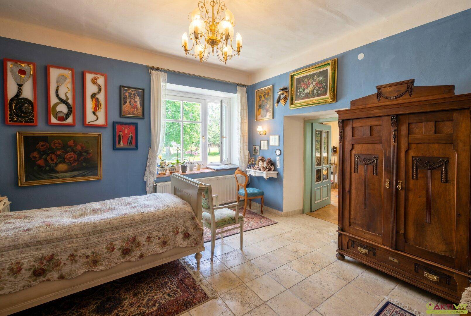 Farbenfrohes Schlafzimmer mit blauen Wänden, Fliesenboden und großem Fenster.