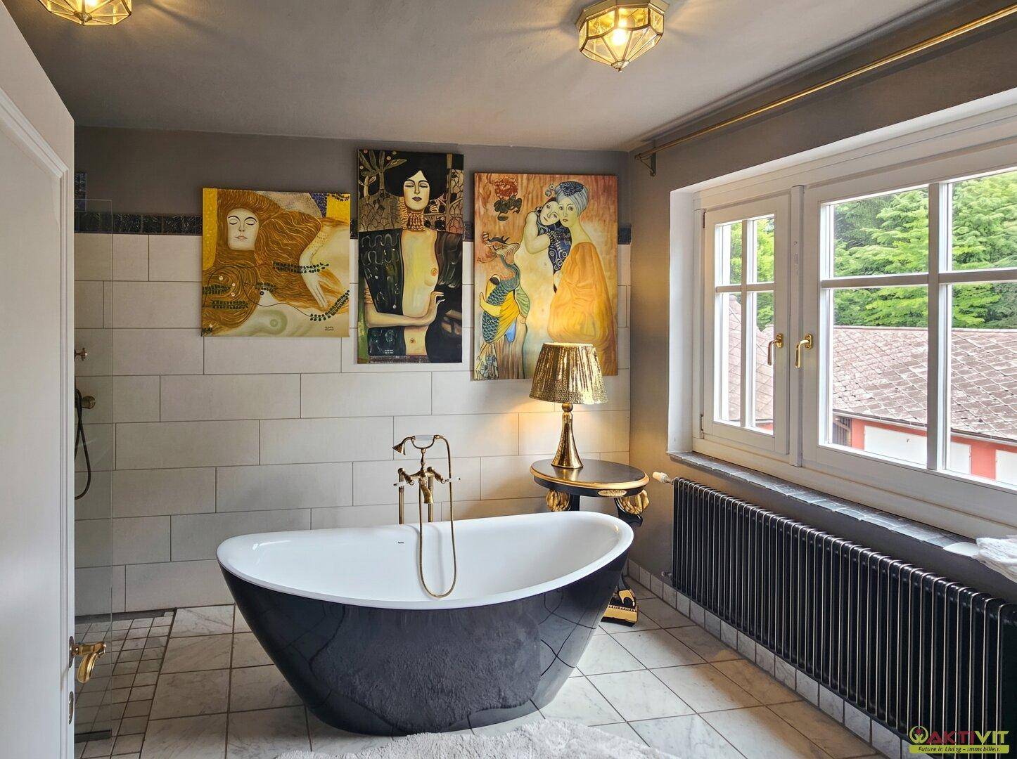 Stilvolles Badezimmer mit freistehender Badewanne, Fenster und Kunstwerken.