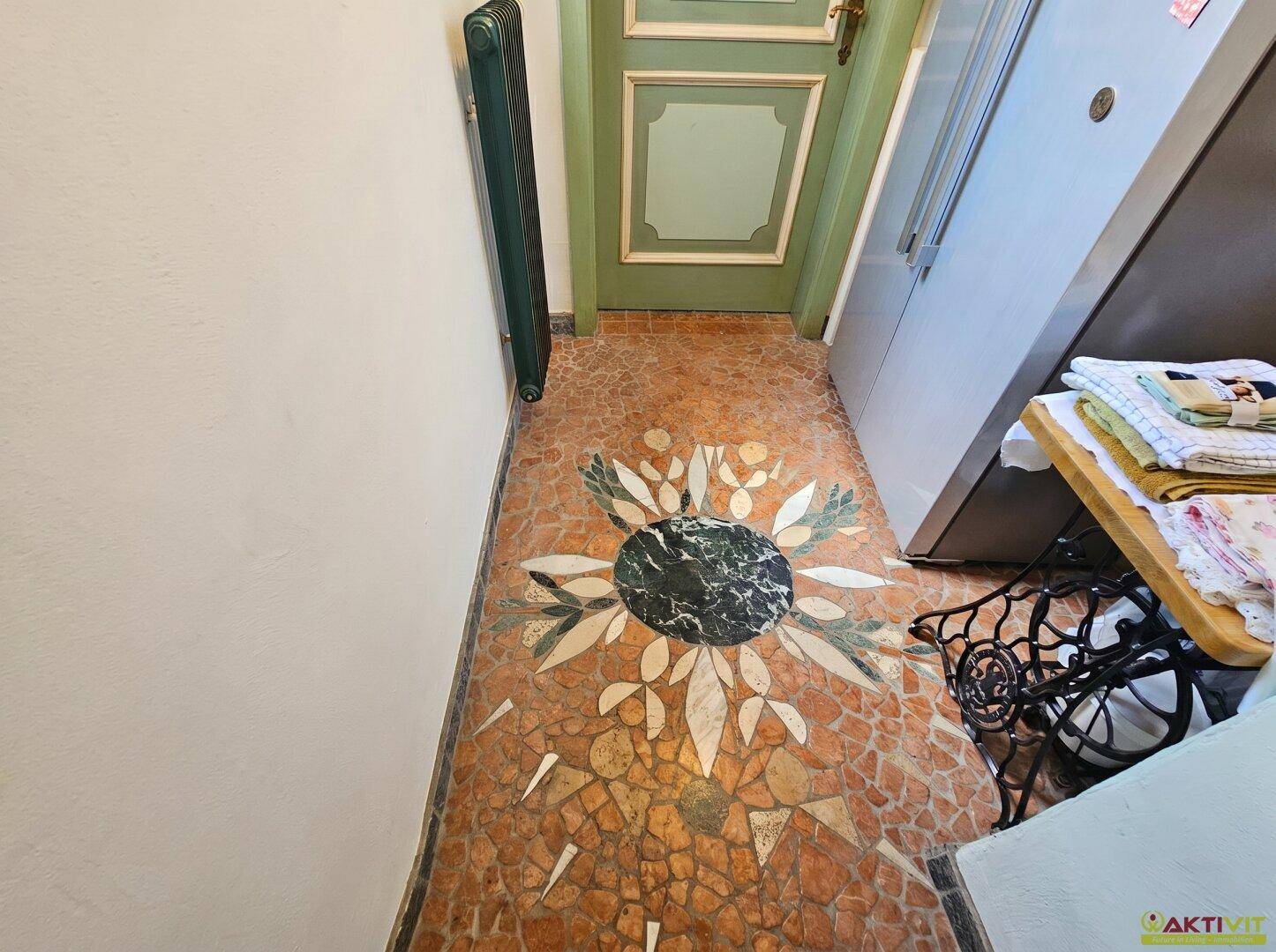 Dekorativer Fliesenboden mit floralem Muster in einem schmalen Durchgangsbereich.