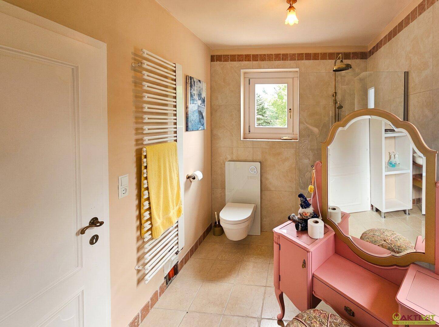 Helles Badezimmer mit Dusche, WC, beheiztem Handtuchhalter und Schminktisch.