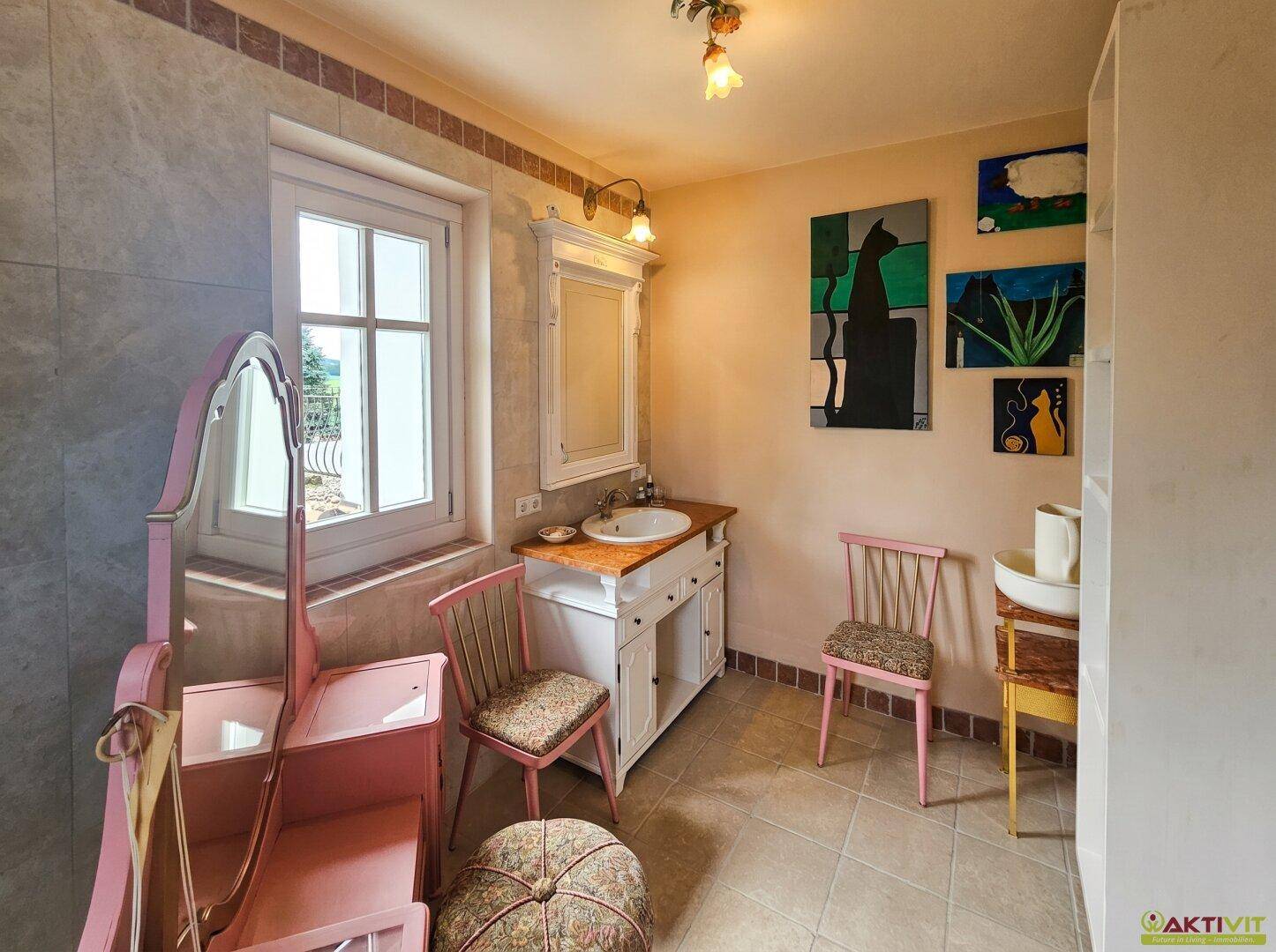 Geräumiges Badezimmer mit Waschtisch, Spiegel und Fenster für Tageslicht.