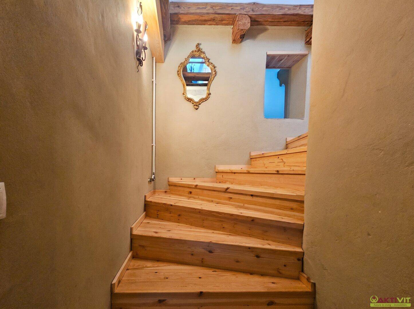 Rustikale Holztreppe mit freiliegenden Balken und Wandspiegel.