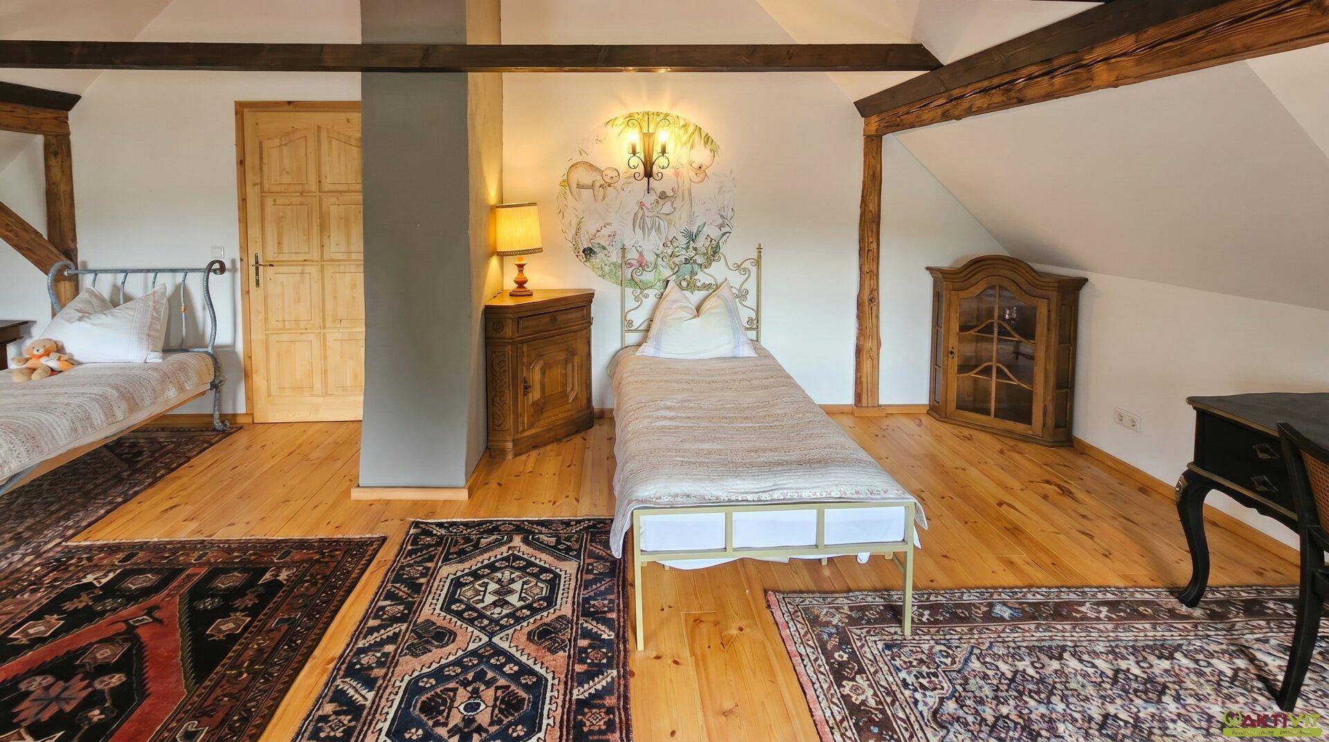 Dachgeschoss-Schlafzimmer mit Holzbalken, Einzelbetten und Holzboden.