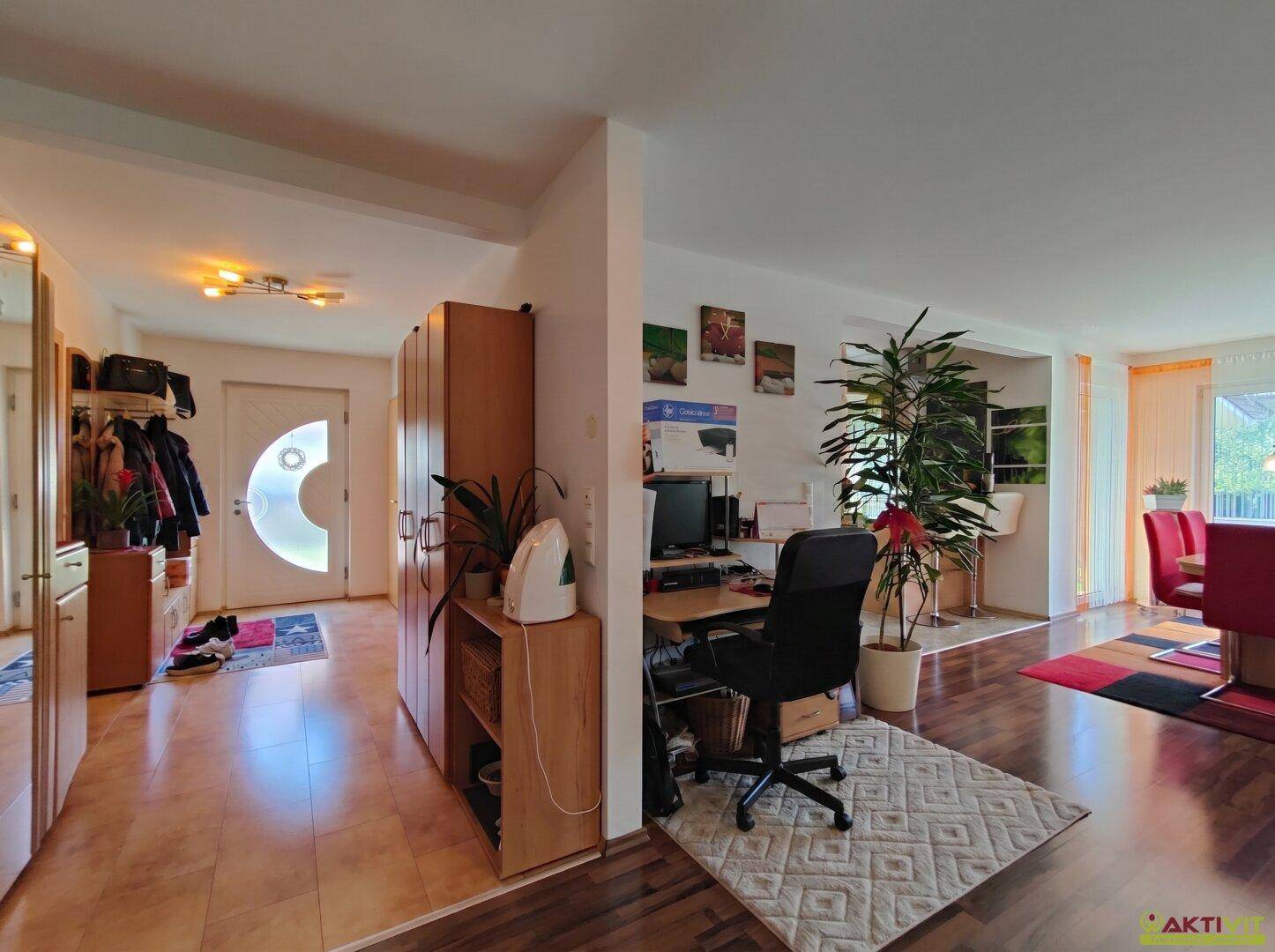 Eingangsbereich mit Fliesenboden, Garderobe und Blick in den offenen Wohn- und Essbereich.