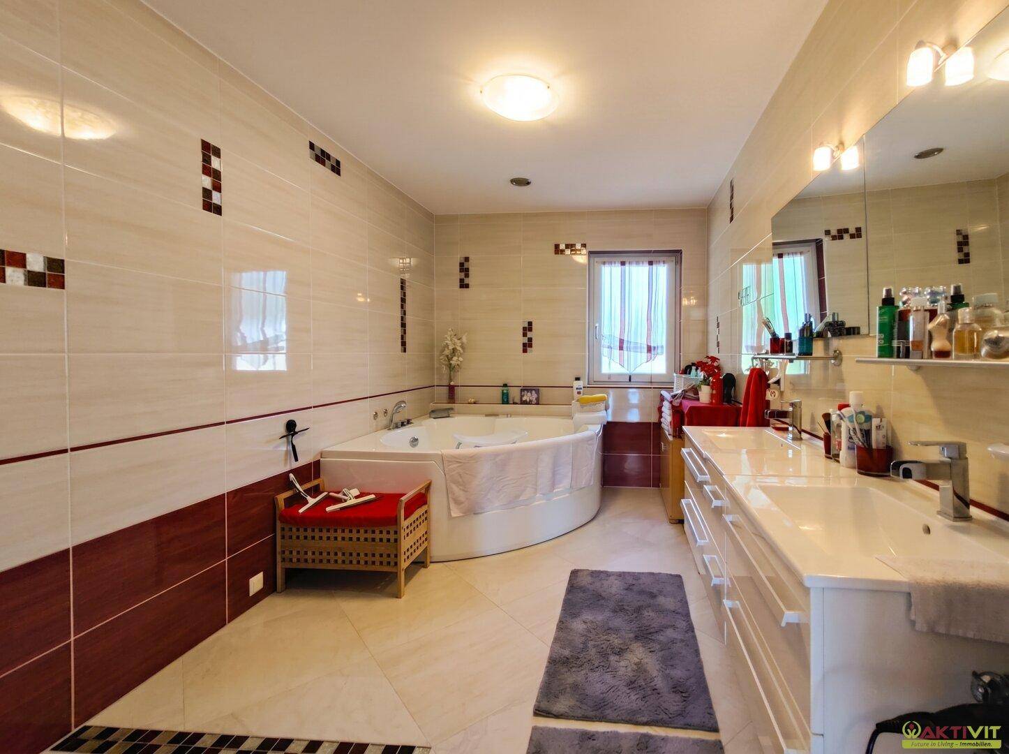 Geräumiges Badezimmer mit Eckbadewanne, Doppelwaschbecken und Fenster für Tageslicht.