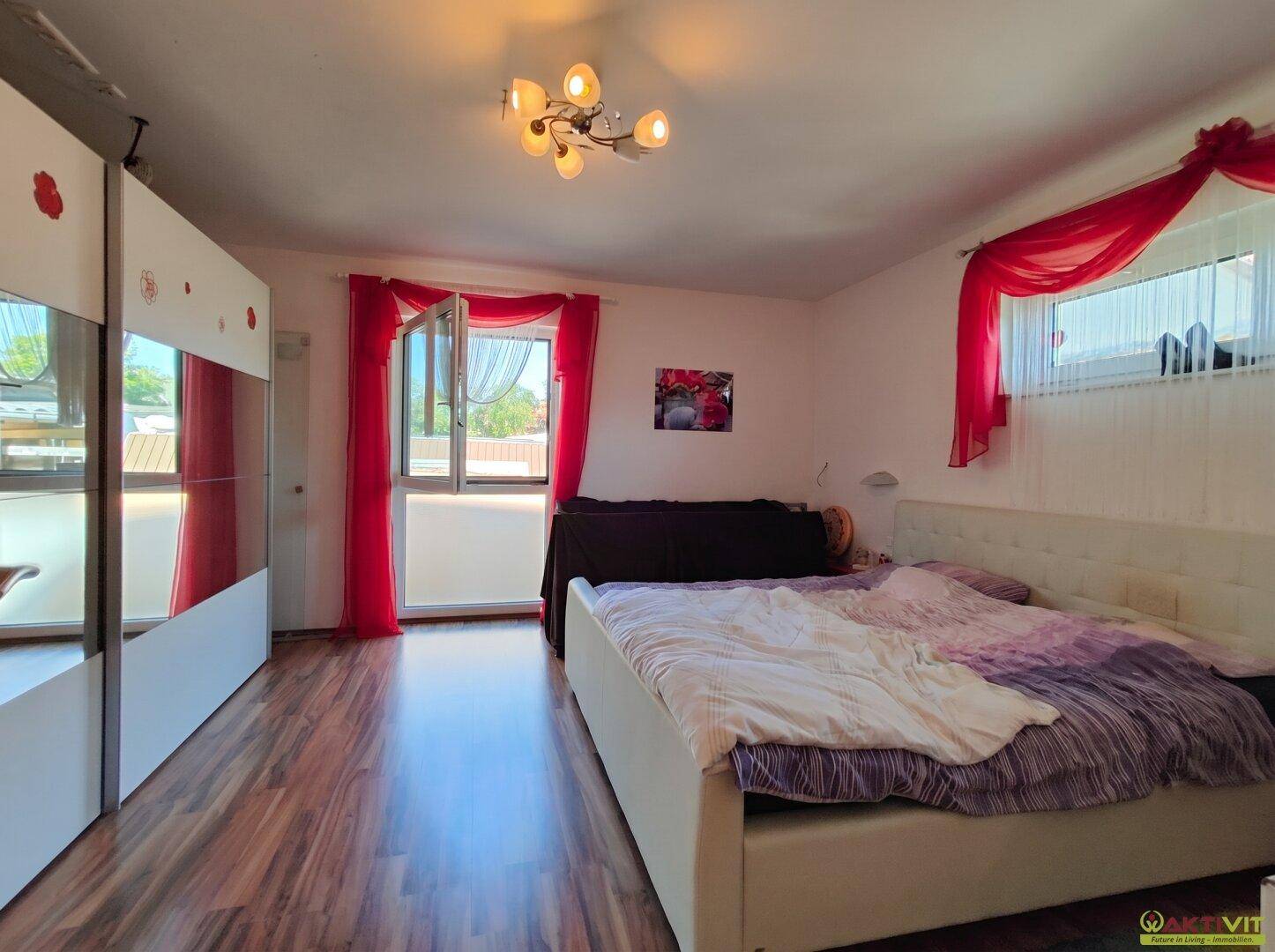 Helles Schlafzimmer mit Doppelbett, Spiegelschrank und Zugang zu einem Außenbereich.