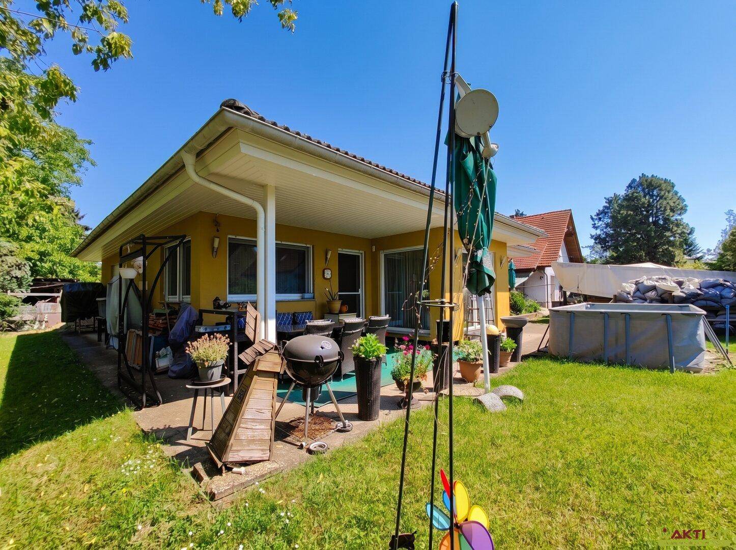 Hinterhof mit Rasenfläche, Terrasse, Grillbereich und einem aufgestellten Pool.
