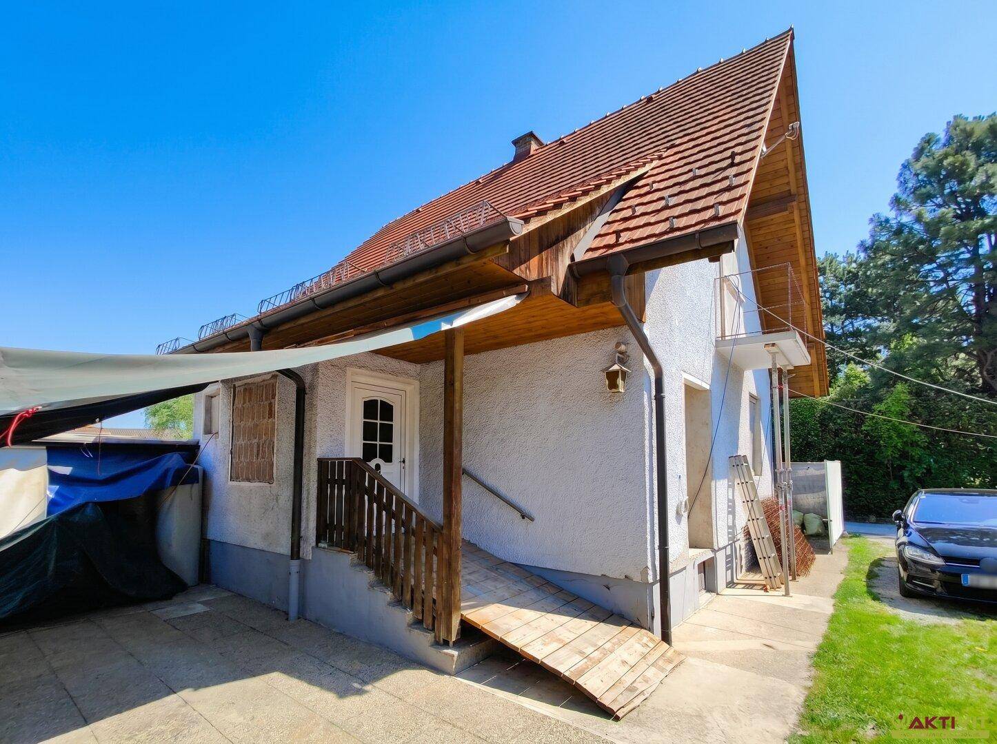 Eingangsbereich eines älteren Gebäudes mit Holzrampe und Treppe für barrierefreien Zugang.