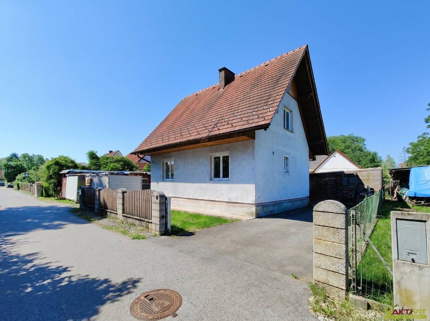 Einfamilienhaus mit Satteldach und gepflasterter Einfahrt in ländlicher Umgebung.
