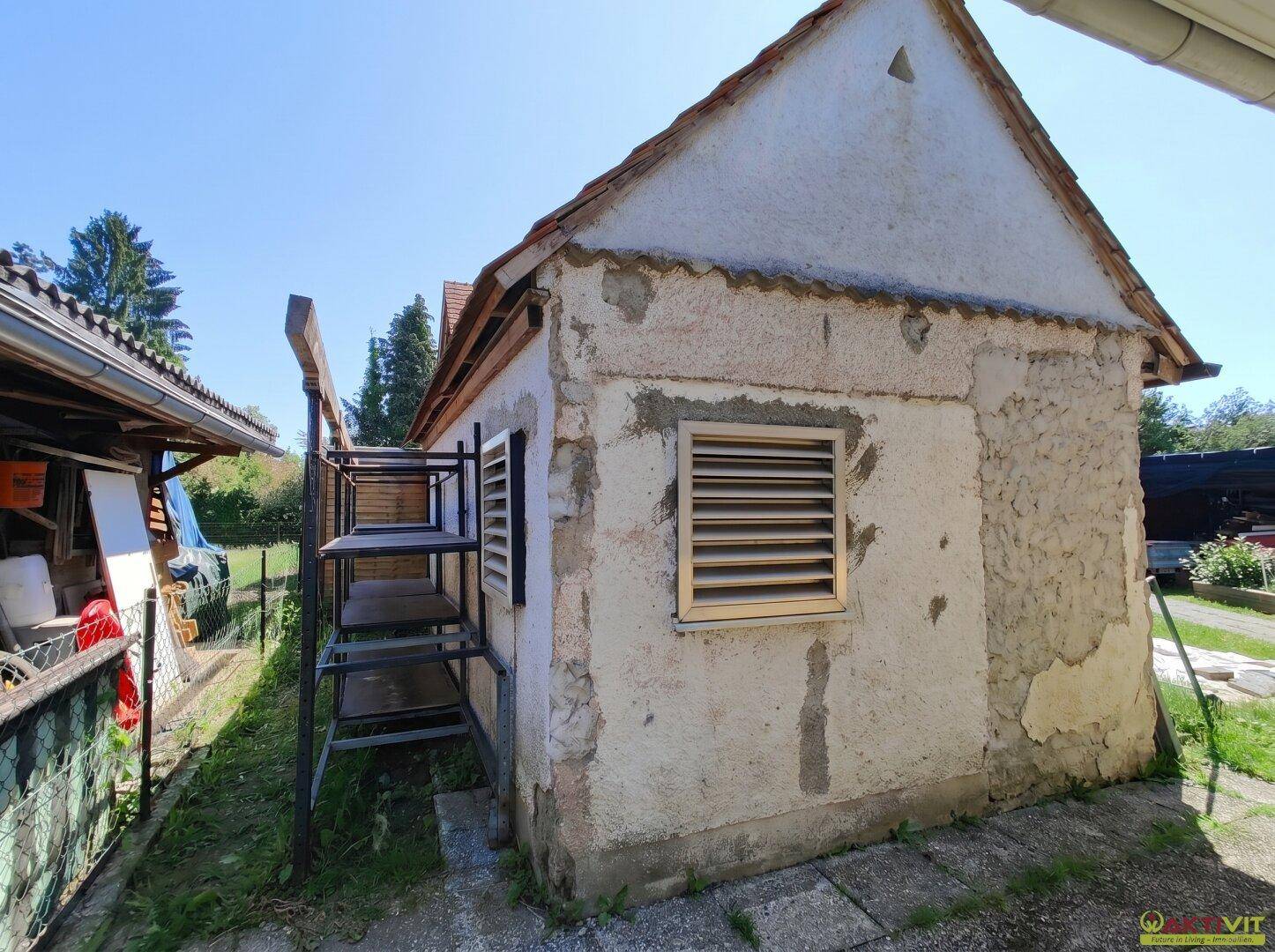 Seitenansicht des Nebengebäudes mit verputzter Fassade und kleinen Fenstern.