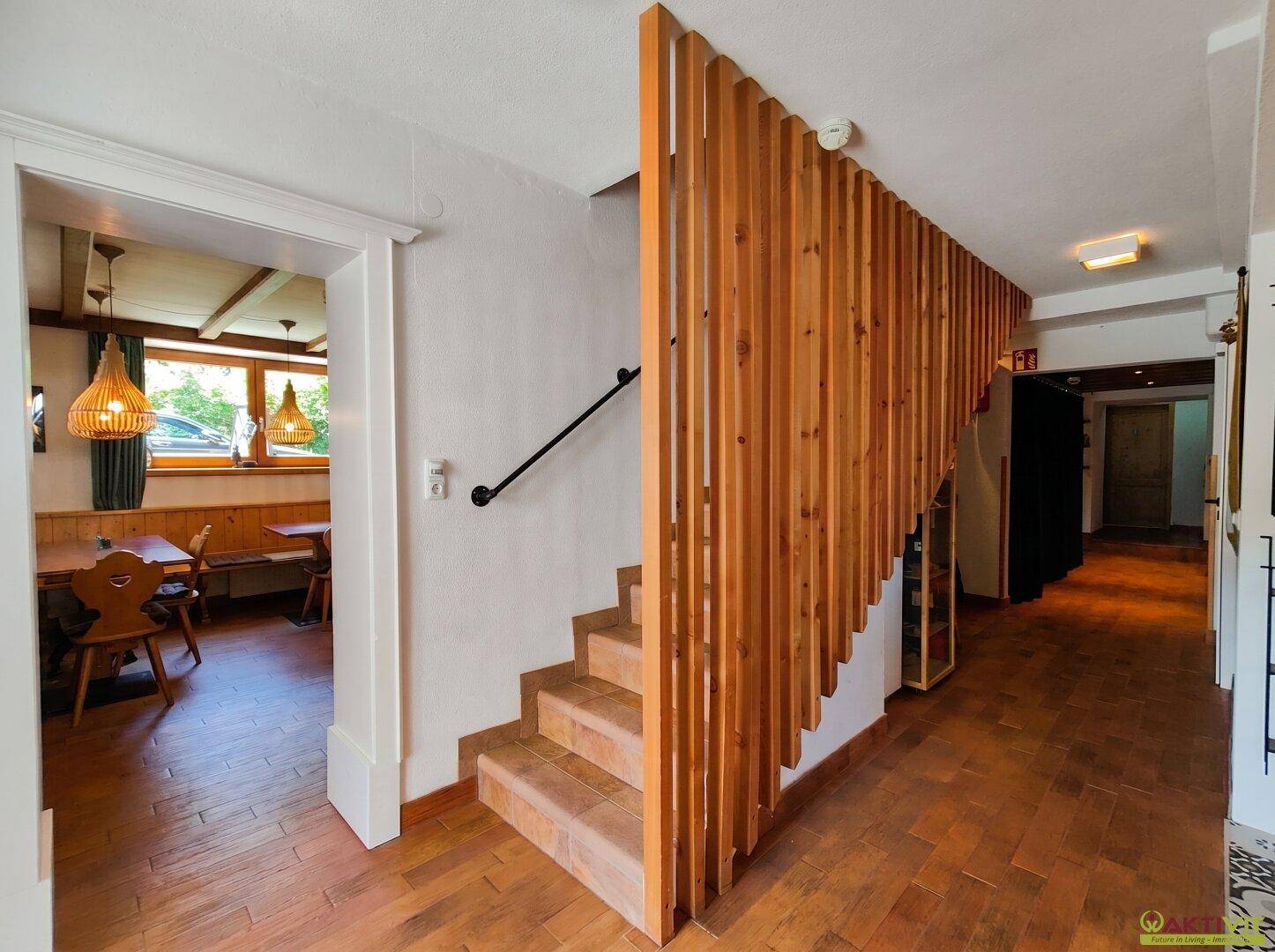 Flur mit Holztreppe und einer dekorativen Holzlamellenwand, die den Raum strukturiert.