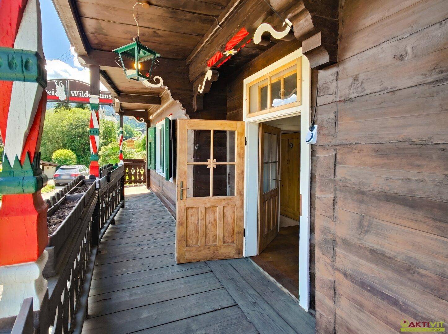 Traditioneller Holzbalkon mit Blick auf die umliegende Landschaft und die Berge.