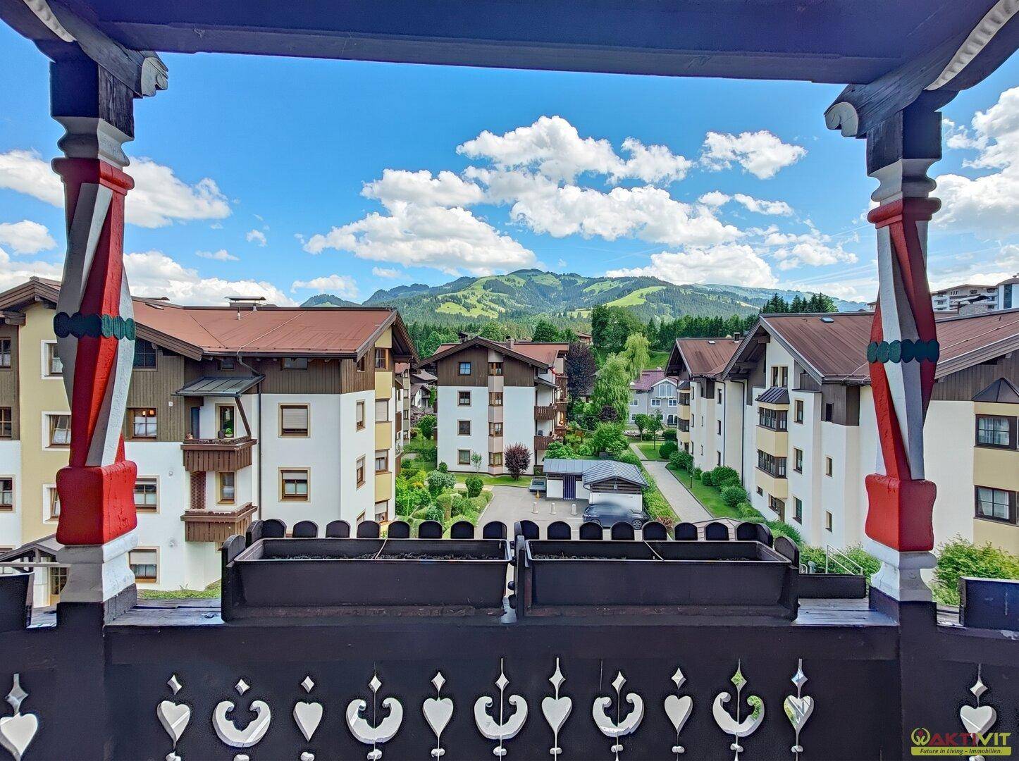 Panoramablick vom Balkon auf die umliegenden Gebäude und die majestätische Berglandschaft.
