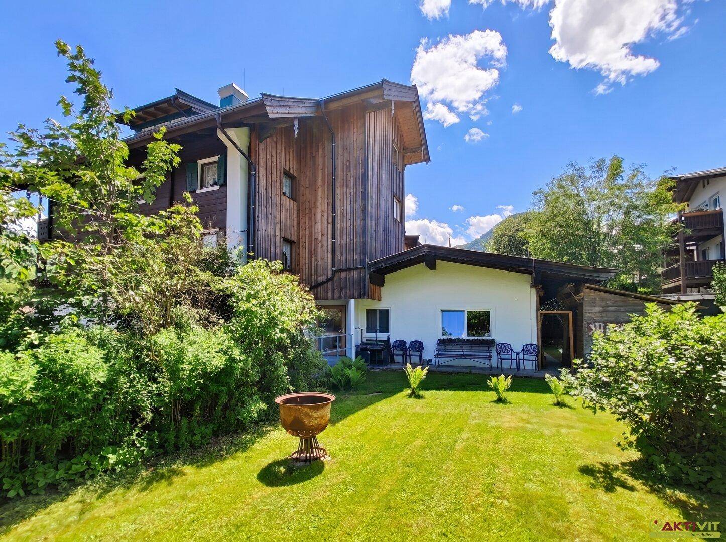 Großer grüner Gartenbereich hinter dem Haus mit Rasenfläche und Sitzgelegenheiten im Freien.