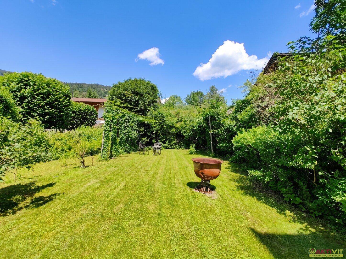 Weitläufiger, gepflegter Garten mit großer Rasenfläche, umgeben von Bäumen und Sträuchern.