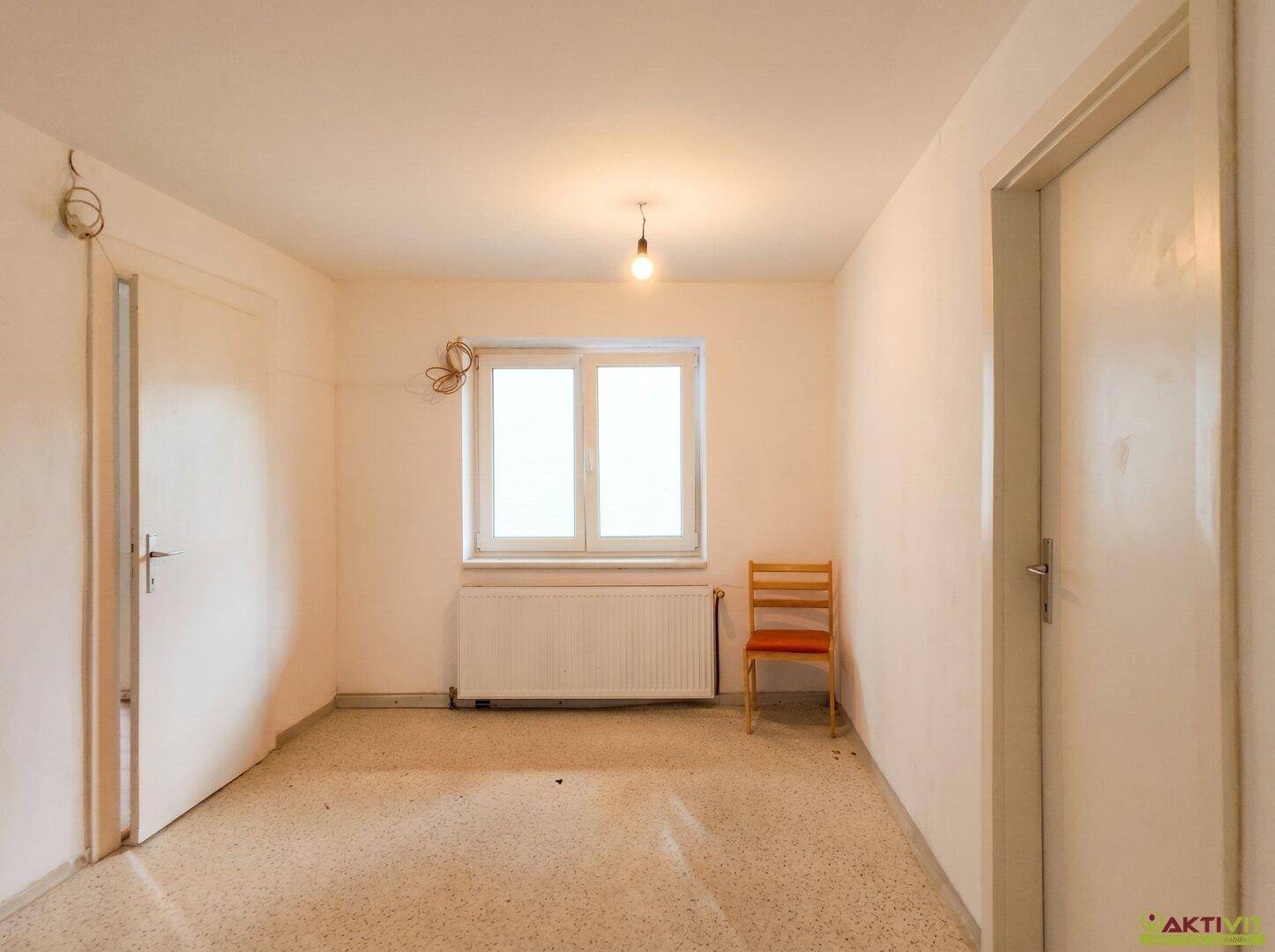 Schlafzimmer mit hellem Boden, weißen Wänden und einem Fenster für natürliches Tageslicht.