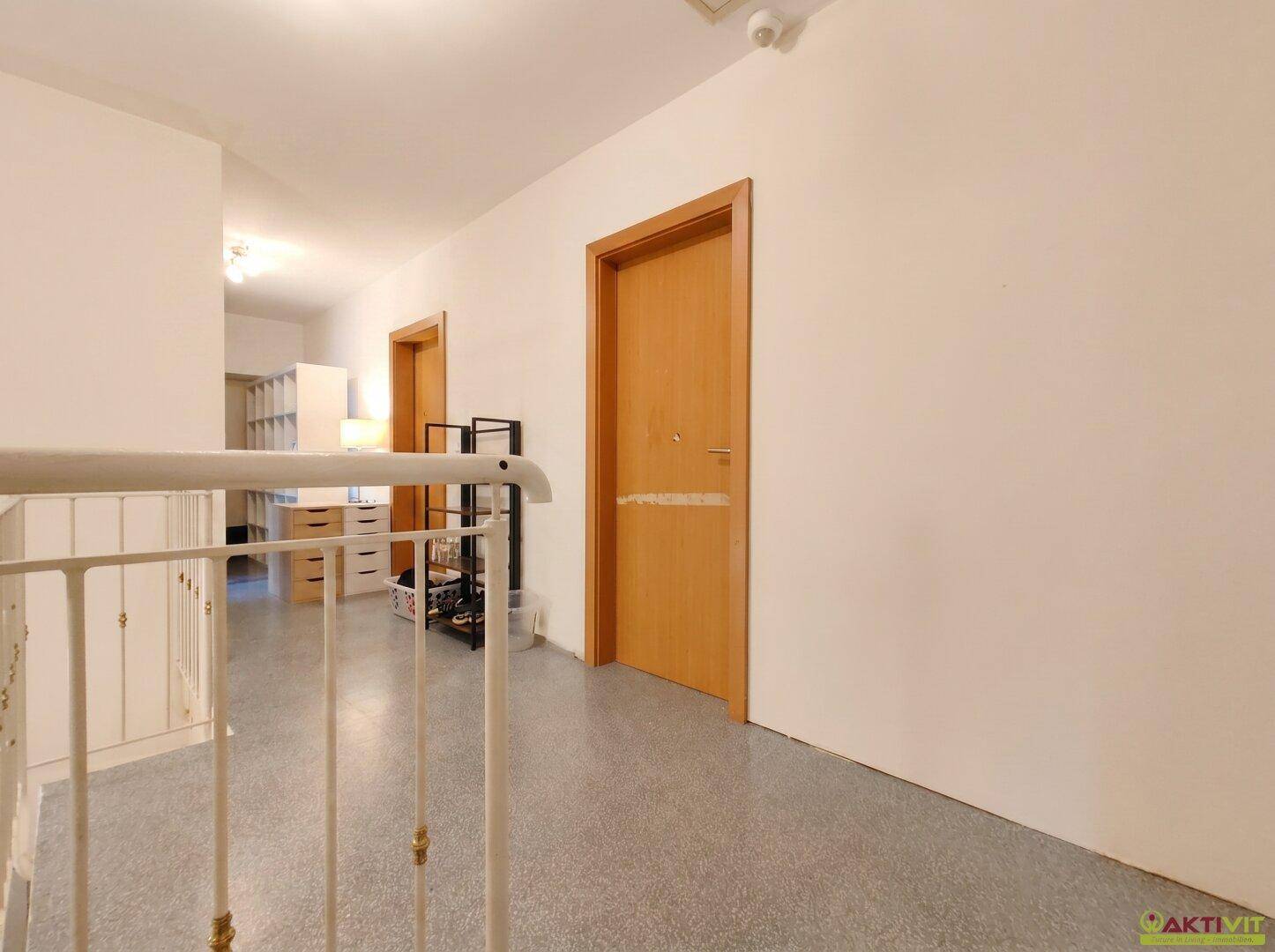 Heller Flur im Obergeschoss mit Terrazzoboden und schlichten Holztüren.