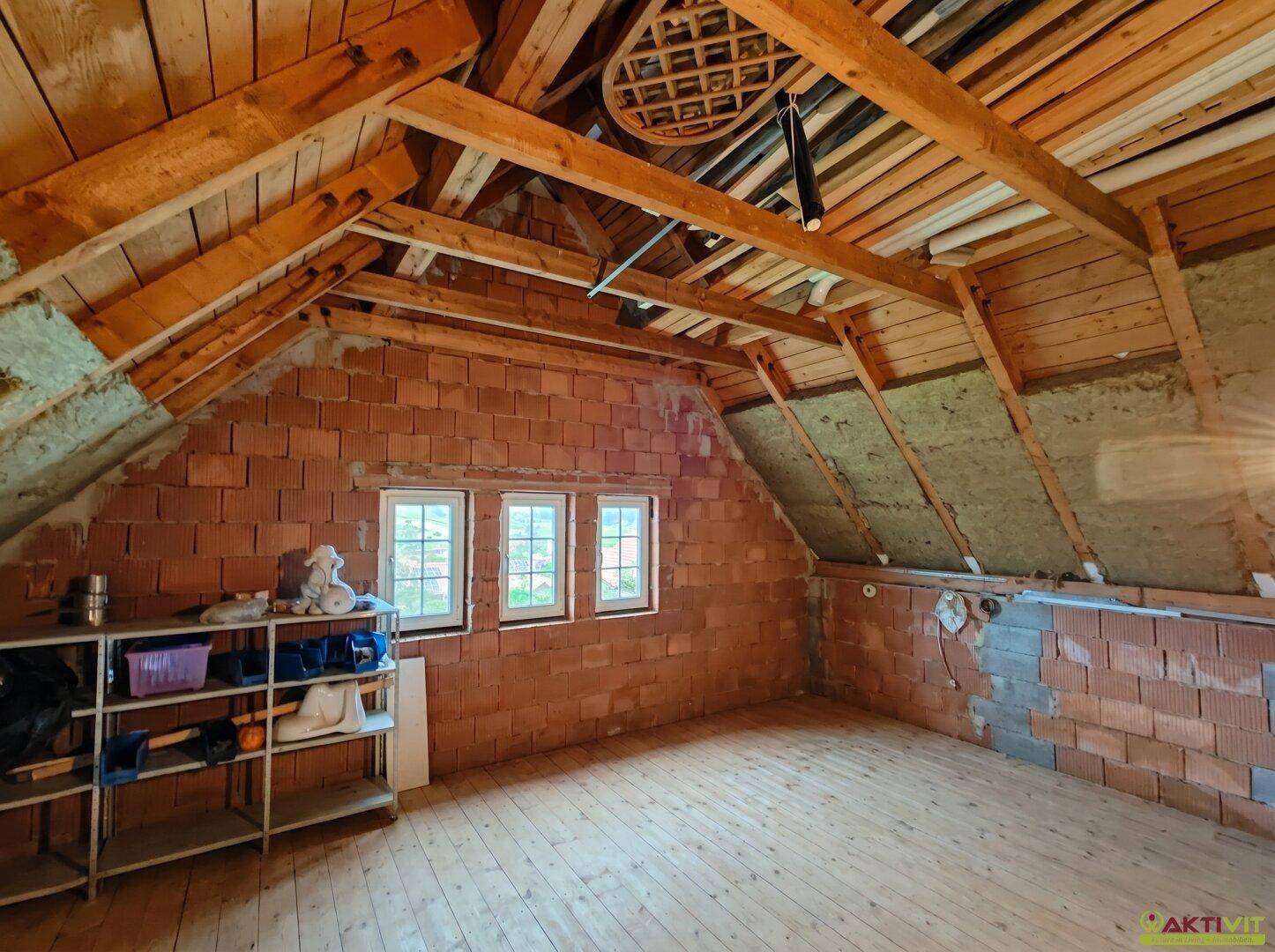 Unausgebauter Dachboden mit sichtbaren Holzbalken und Ziegelwänden, bereit zum Ausbau.